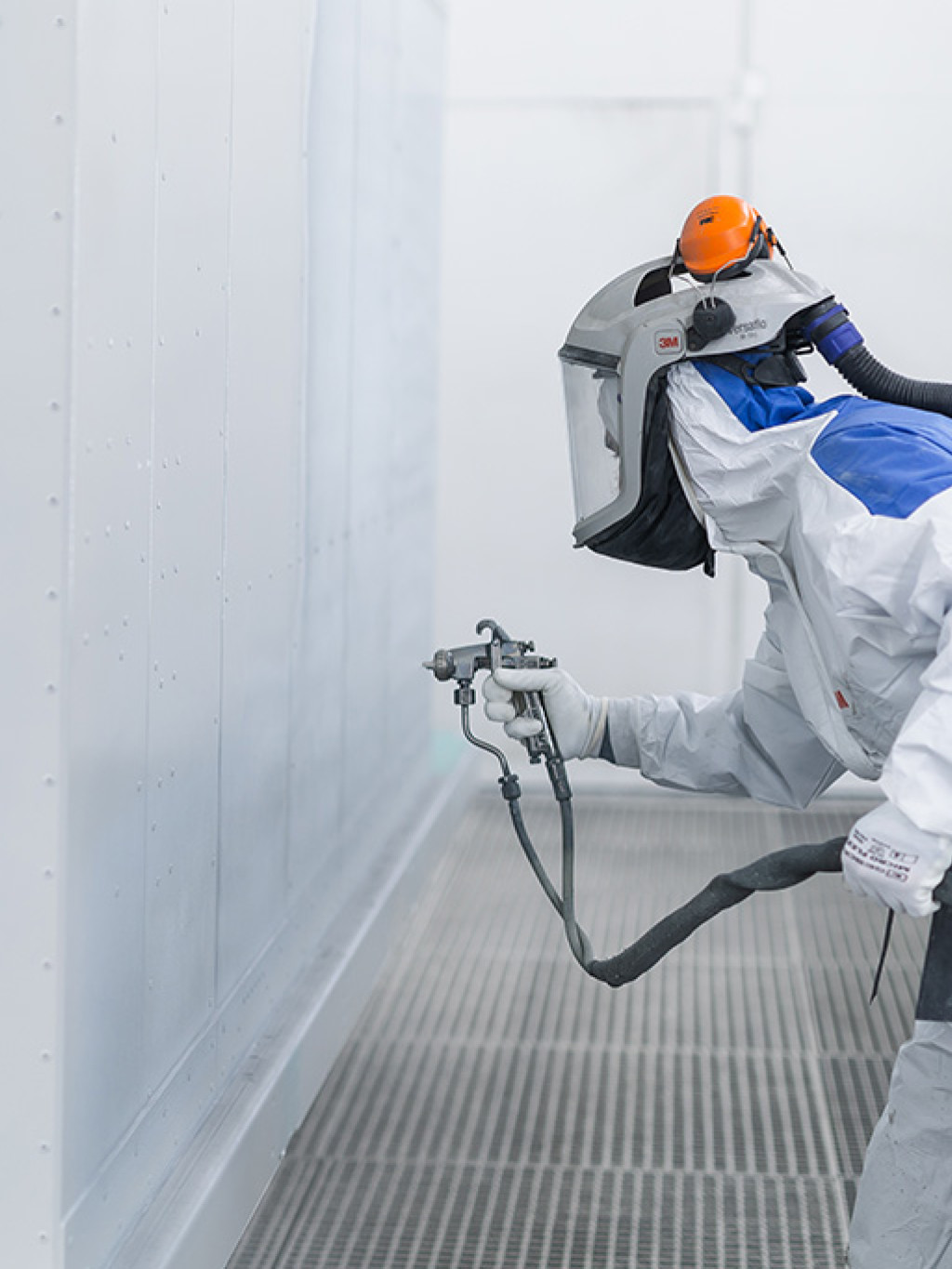 Mitarbeiter in Schutzanzug lackiert Element mit grauer Farbe für Zollinger Thermobeschichtungen AG